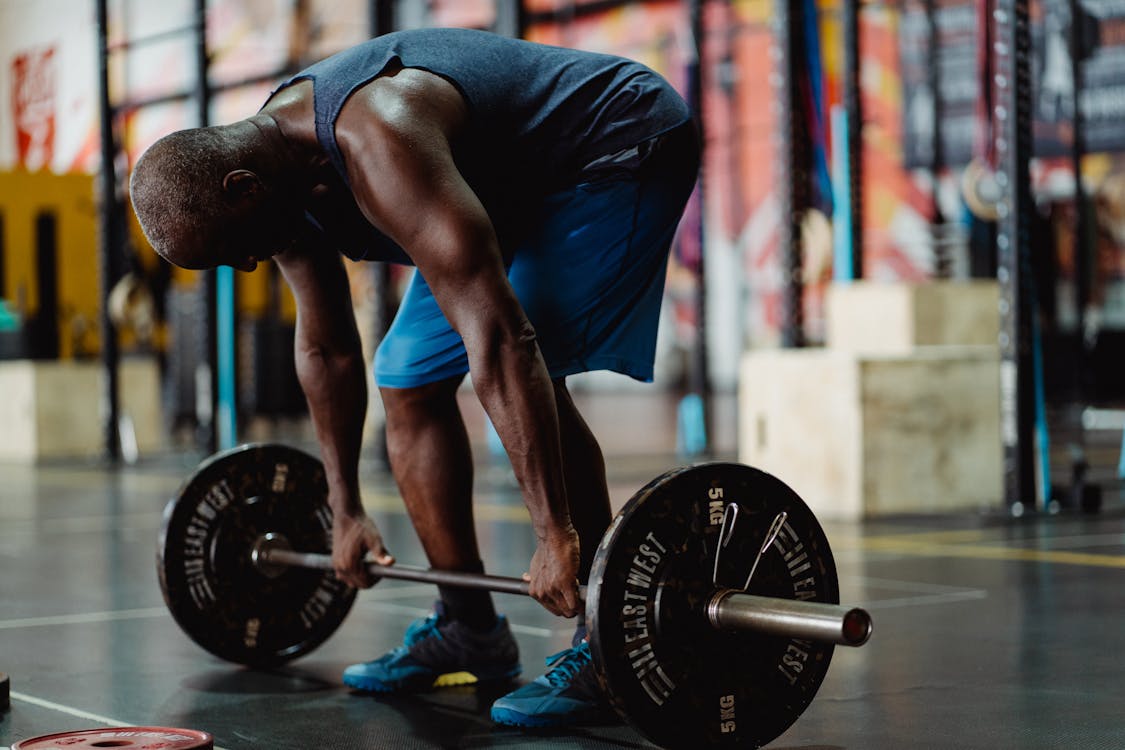 Free Man in Blue Tank Top and Blue Shorts Lifting a Barbell Stock Photo