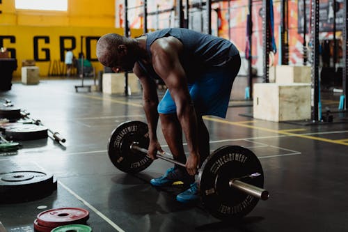 Free Man in Blue Tank Top and Blue Shorts Holding a Barbell Stock Photo