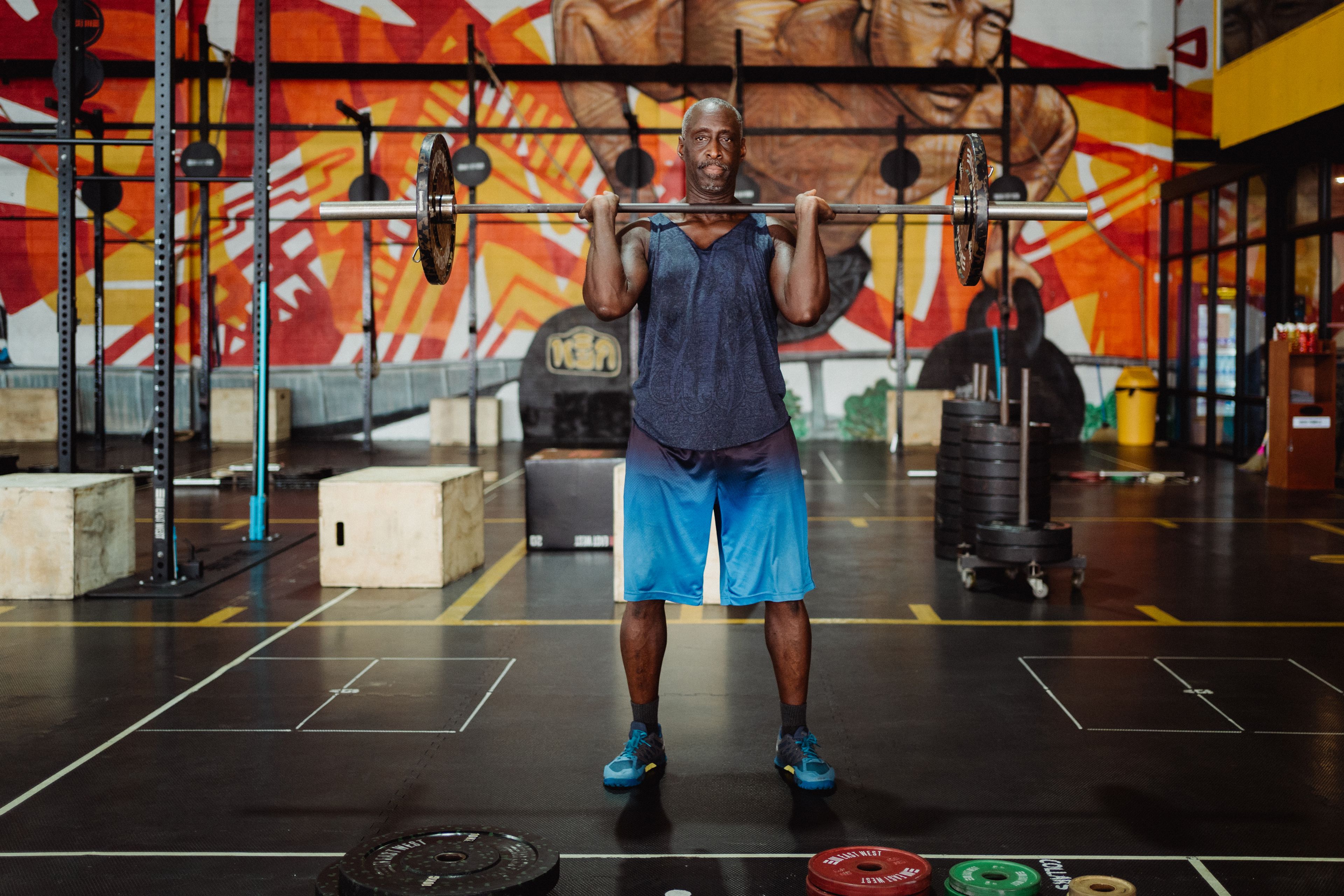 Muscular man lifting barbell in a colorful gym, exuding strength and fitness.