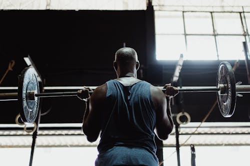 Free Man in Blue Tank Top Lifting a Barbell Stock Photo