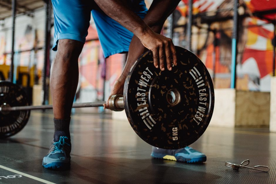 An athletic man preparing for a weightlifting session inside a vibrant gym.