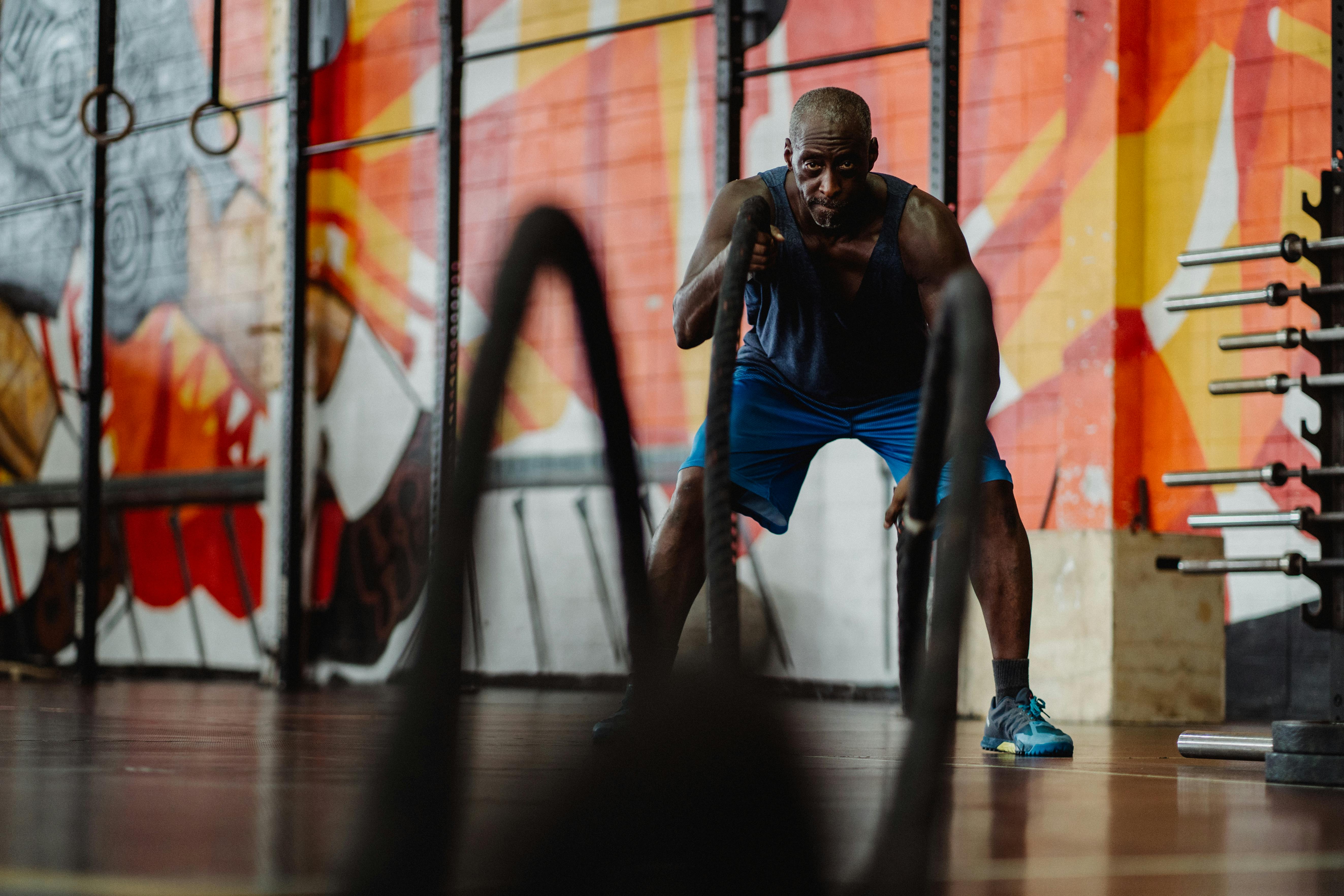 man in blue shorts exercising with battle ropes