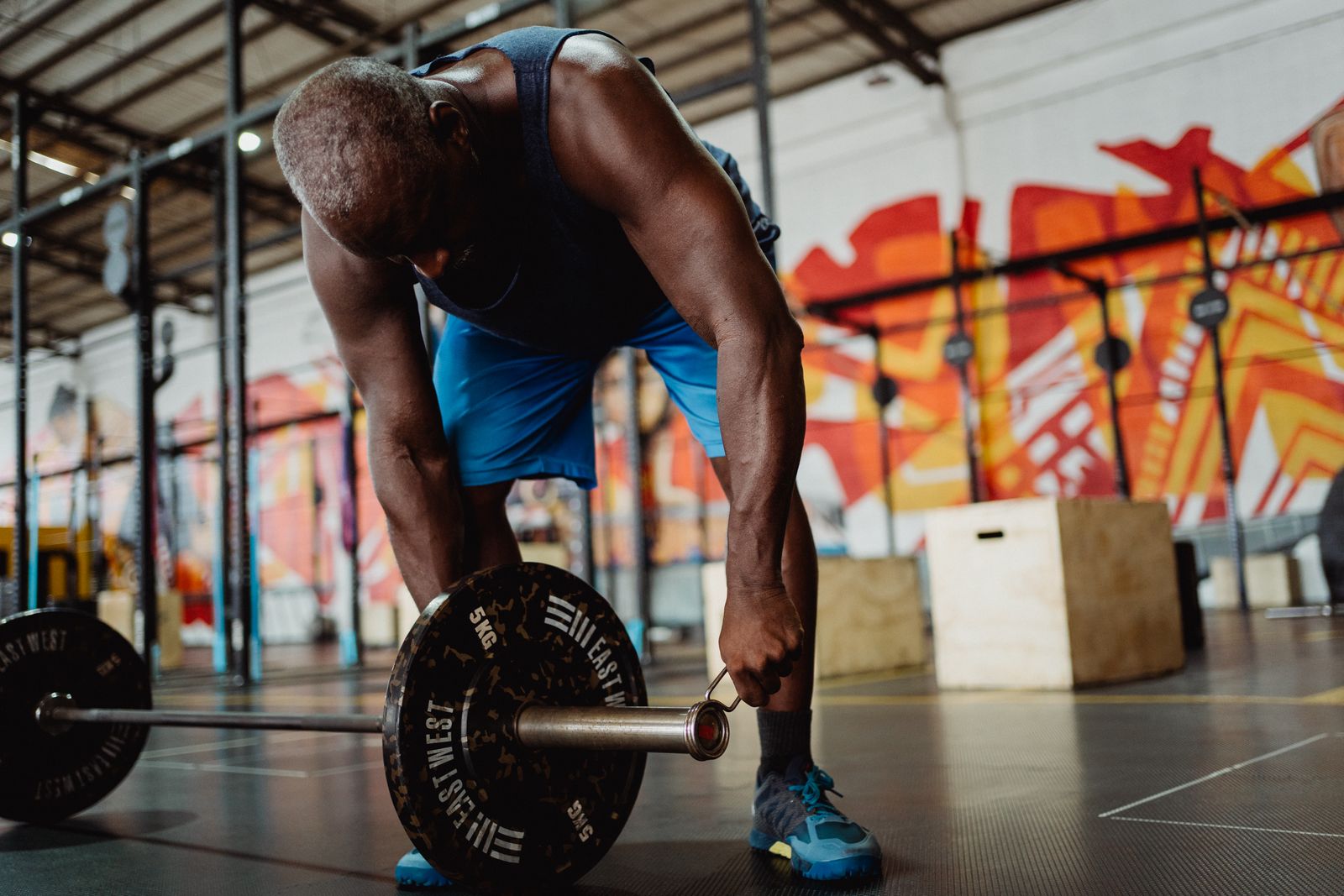 Lifter setting up a heavy barbell in a gym with a colourful mural