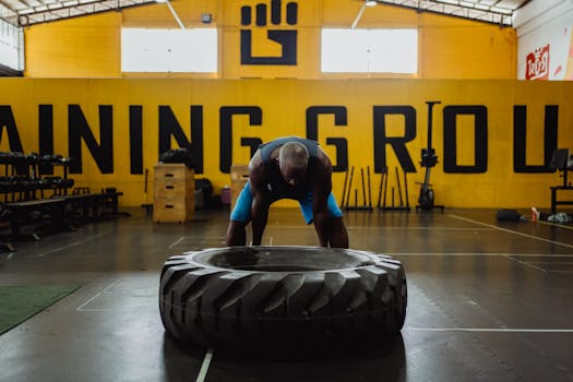 A strong athlete lifts a heavy tire during an indoor gym workout, showcasing strength and determination.