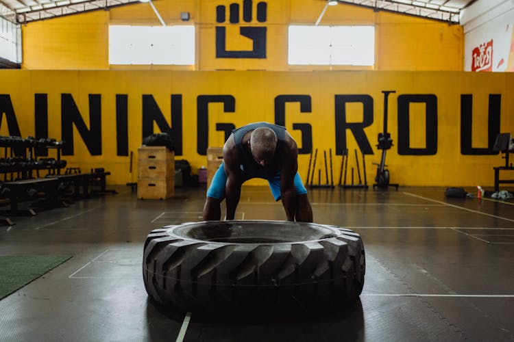 Man In Blue Shorts Lifting Huge Tire