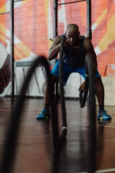 Man engaged in a dynamic battle rope exercise at a gym, showcasing strength and focus.