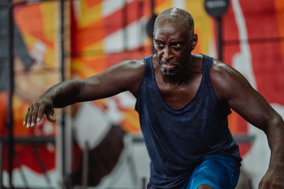 A strong, focused man engages in an intense indoor workout, showing determination and strength.