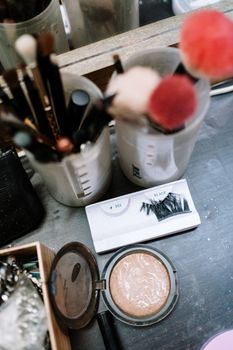 Overhead shot of cosmetic tools including brushes and eyelashes on a dressing table.