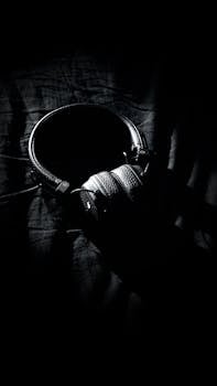 Monochrome image of headphones on a dark blanket, conveying a cozy and relaxed atmosphere.