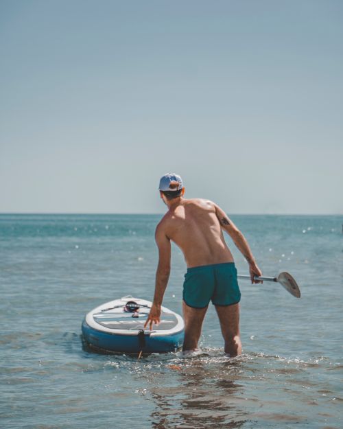 Free Back view of a man paddleboarding in Vasto, Italy, with a clear sky and calm sea. Stock Photo