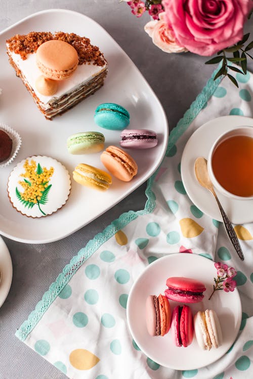 Macaroons and small cakes on table in cozy kitchen