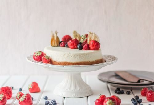 Free Appetizing cake decorated fresh berries placed on ceramic cake plate on white wooden table Stock Photo