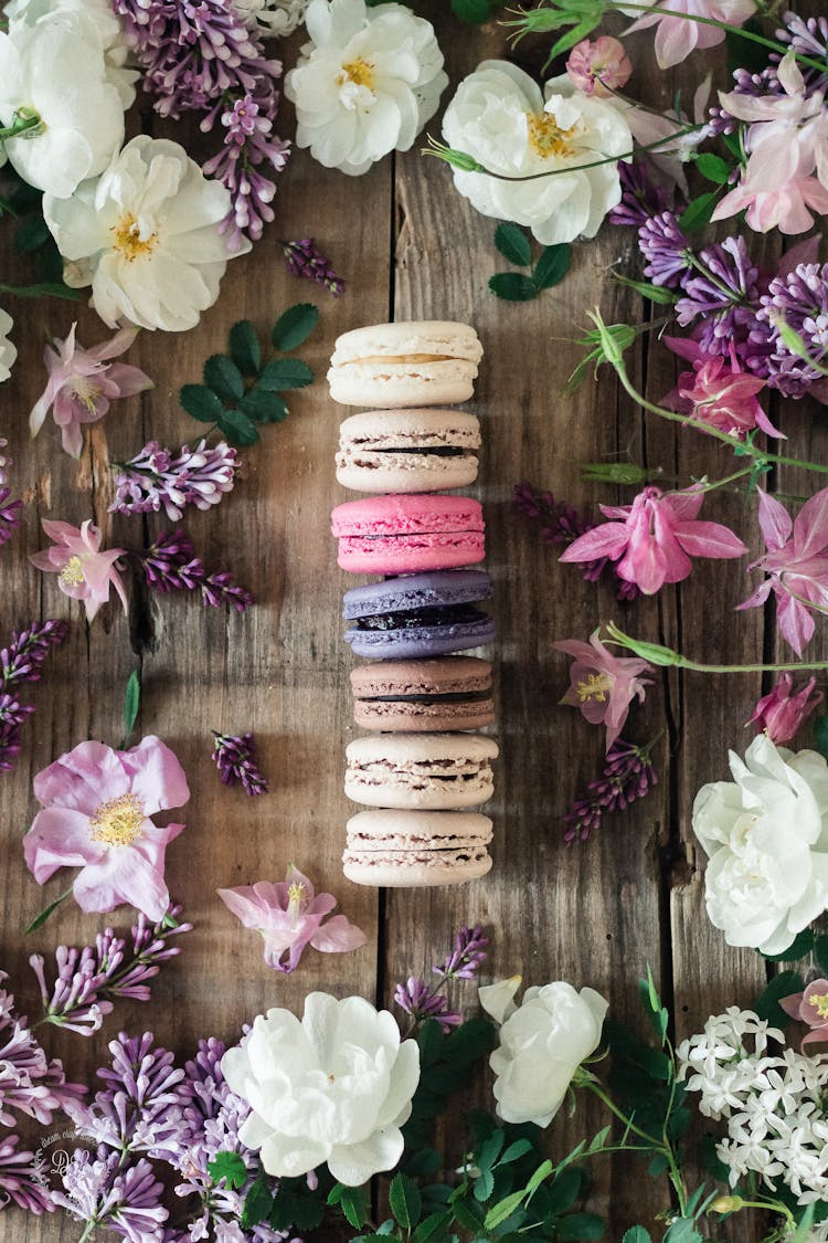 Colorful Macarons Placed On Wooden Table With Flowers