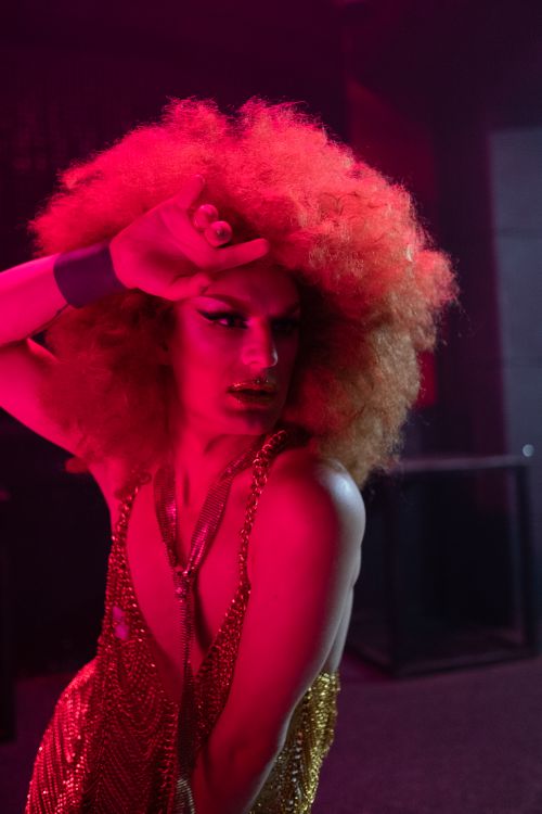 Free A colorful drag queen performer showcasing an expressive pose in a lively nightclub setting. Stock Photo