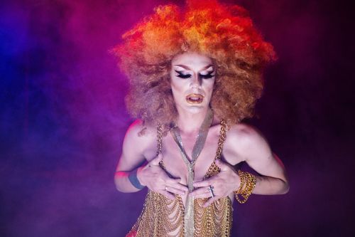 Free Vibrant drag queen performance featuring bold makeup and costume in a smoky nightclub atmosphere. Stock Photo