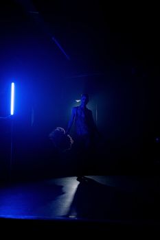 A striking drag performance on stage highlighted by vivid blue lights, exuding elegance and transformation.