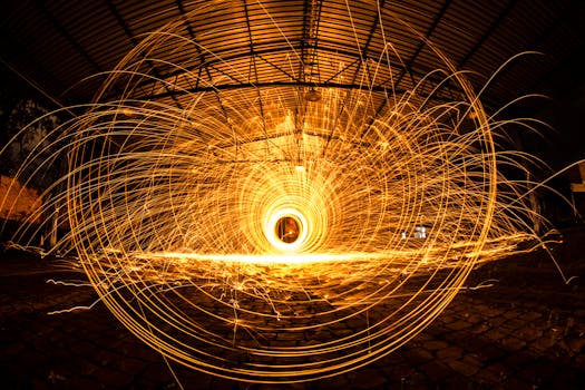 Mesmerizing long exposure of vibrant steel wool sparks creating circular patterns indoors.