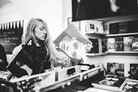 黑白照片中，一名女子正在一家古董音乐商店里浏览黑胶唱片