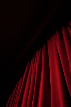 A striking red velvet curtain with dramatic lighting in a theater setting, offering ample copy space.