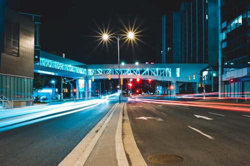 Asphalt road going through illuminated buildings located on city street at night time