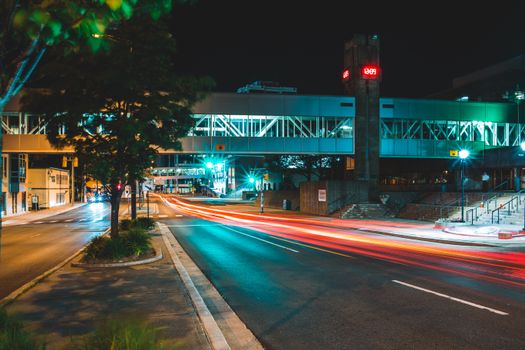 Long exposure urban asphalt road with pedestrian overpass located in modern city at night