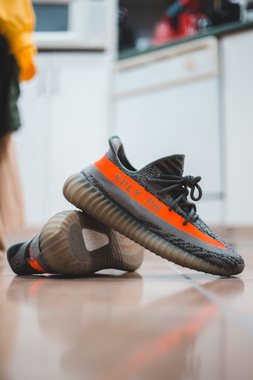 Pair of mens trendy runners of black and orange colors placed on floor in shoe store