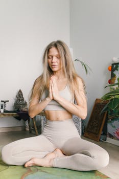 A woman in activewear practices yoga meditation indoors, radiating calm and relaxation.