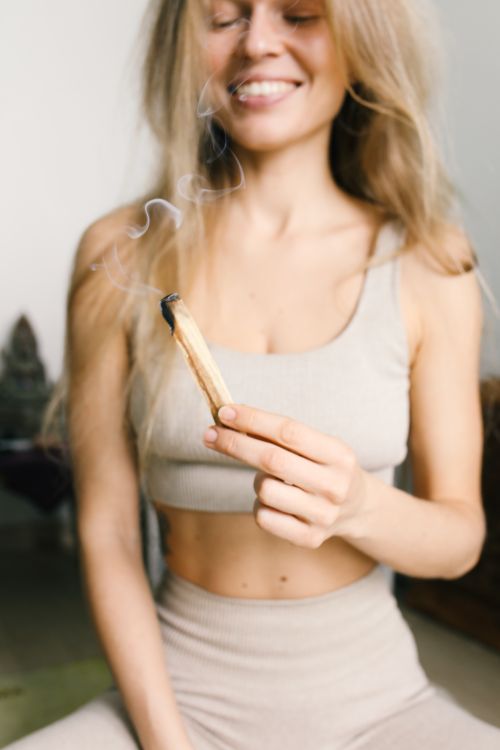 Free Smiling woman performs a spiritual ritual with burning sage indoors. Stock Photo