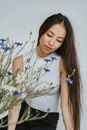 Woman in White Halter Tank Top with Long Hair Sitting Near Flowers