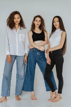 三名女性身着休闲服装，在室内摆出时尚姿势，展现现代时尚趋势