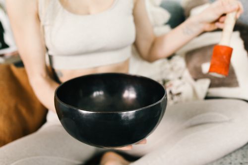 Free Close-up of a woman holding a black singing bowl during meditation indoors. Stock Photo