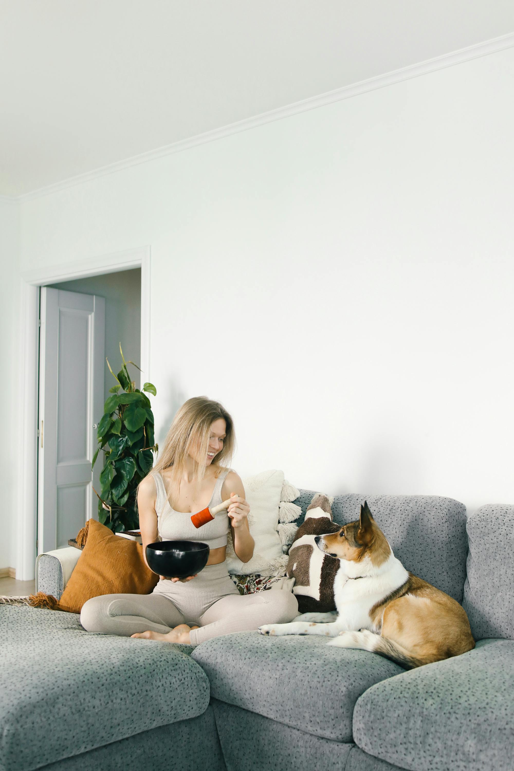 在明亮的房间里，一位女士和她的狗躺在沙发上，享受着温馨舒适的时光