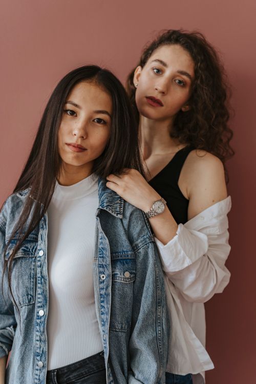 Free Stylish portrait of two young women posing against a pink wall, showcasing diverse fashion and modern style. Stock Photo