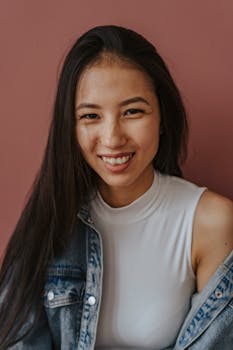 一位穿着牛仔夹克、面带微笑的女人肖像，背景是柔和的棕色