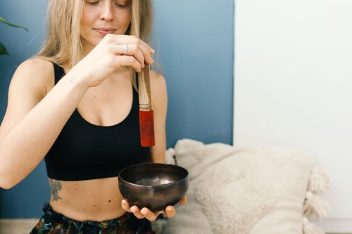 Free Young woman using a singing bowl for meditation. Relaxing indoor setting with a peaceful ambiance. Stock Photo