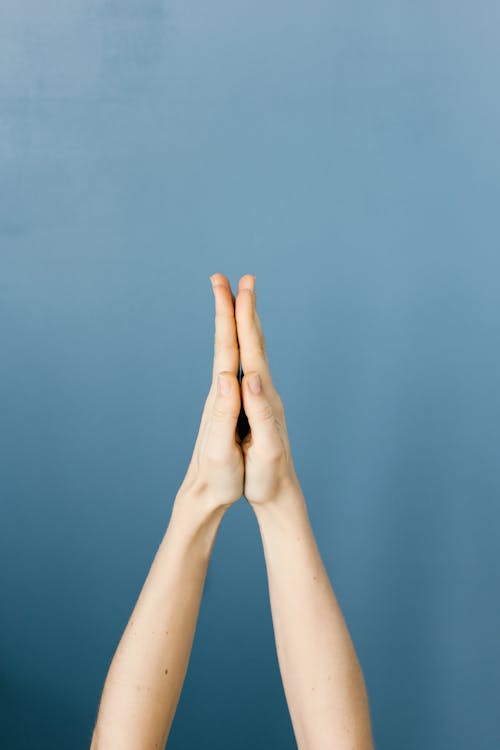 Free Hands Clasped Against Blue Background Stock Photo