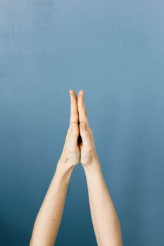 蓝色背景上，特写镜头聚焦于祈祷手势的双手，象征着灵性与冥想