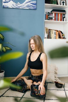 Woman meditating in lotus pose indoors for wellness and relaxation.