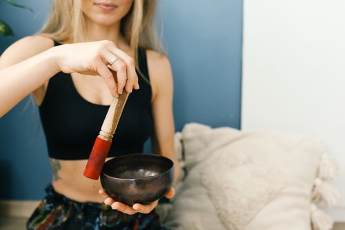 Free A woman in a sports bra uses a Tibetan singing bowl for meditation indoors. Stock Photo
