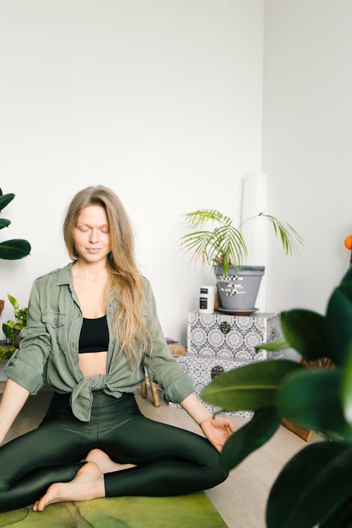 Woman Surrounded by Indoor Plants While Meditating 