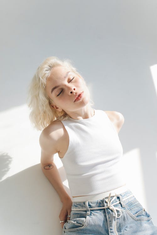 A Woman in White Sleeveless Top Lying on White Surface