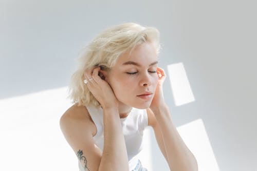 Woman Touching Her Ears While Her Eyes Closed 