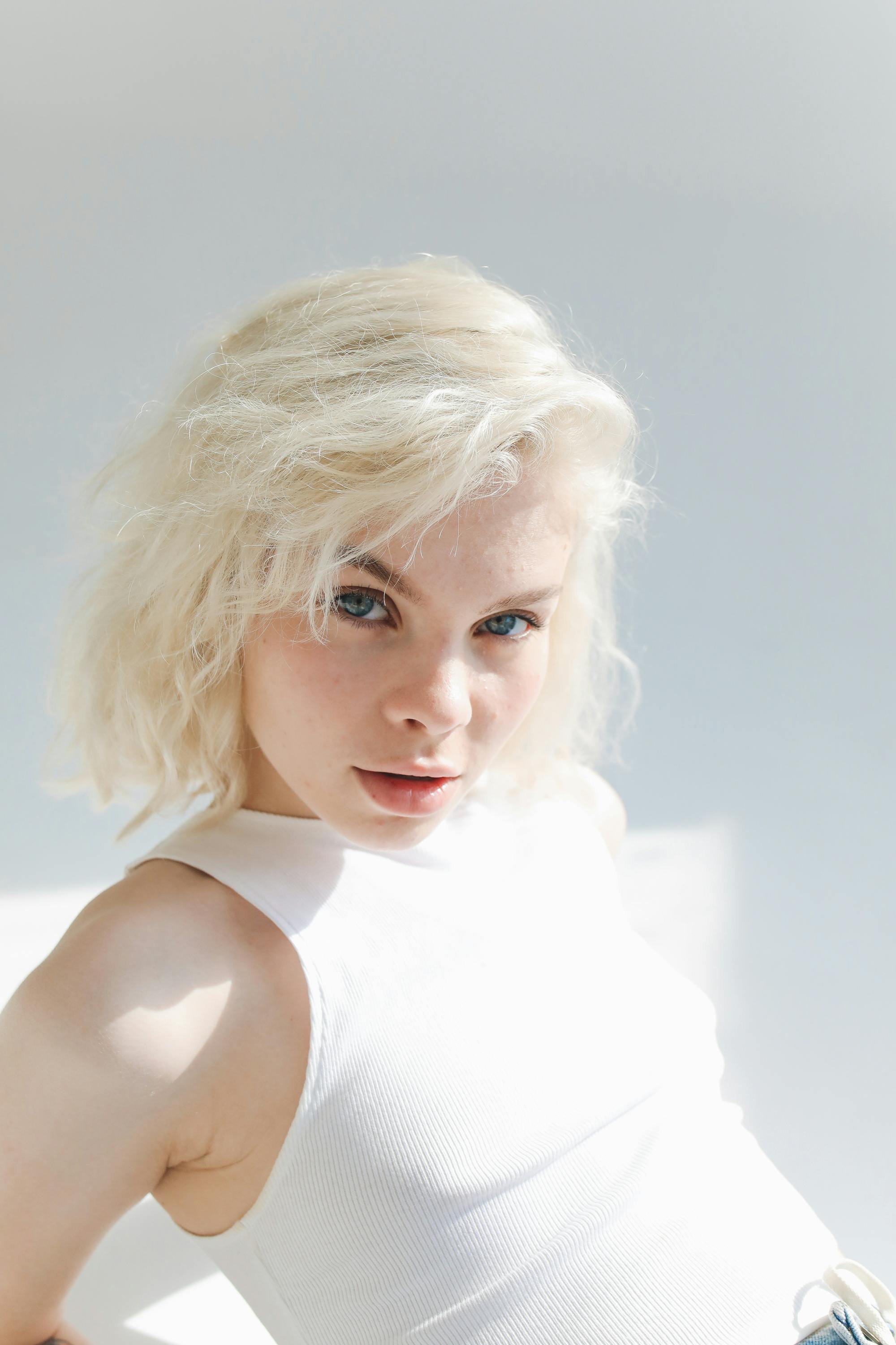 young woman with platinum blonde hair posing in sunlight