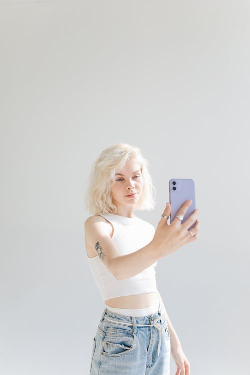 Photo of Girl in White Top Taking Selfie Using Smartphone