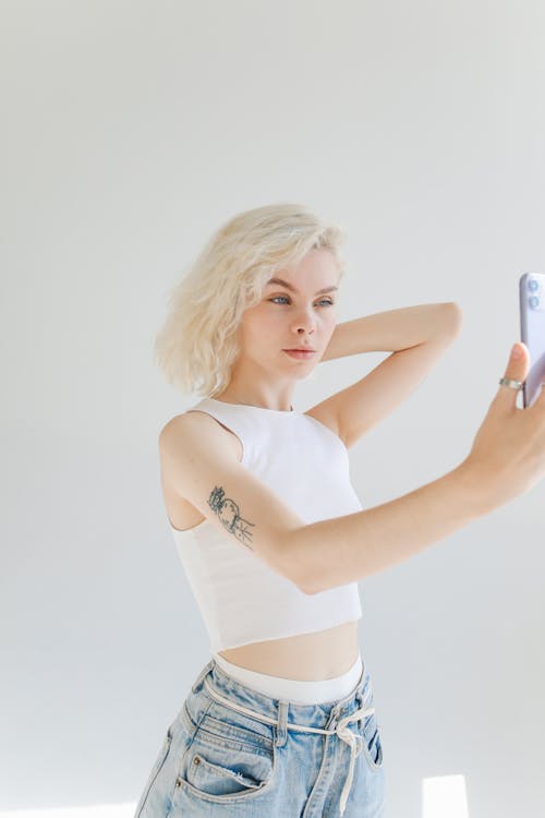 Photo of Girl in White Top Taking Selfie Using Smartphone