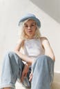 时尚的金发女郎，戴着蓝色帽子和白色上衣，以放松的姿势坐着