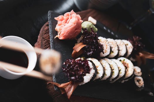 Close-up view of a sushi platter with soy sauce, wasabi, and pickled ginger.