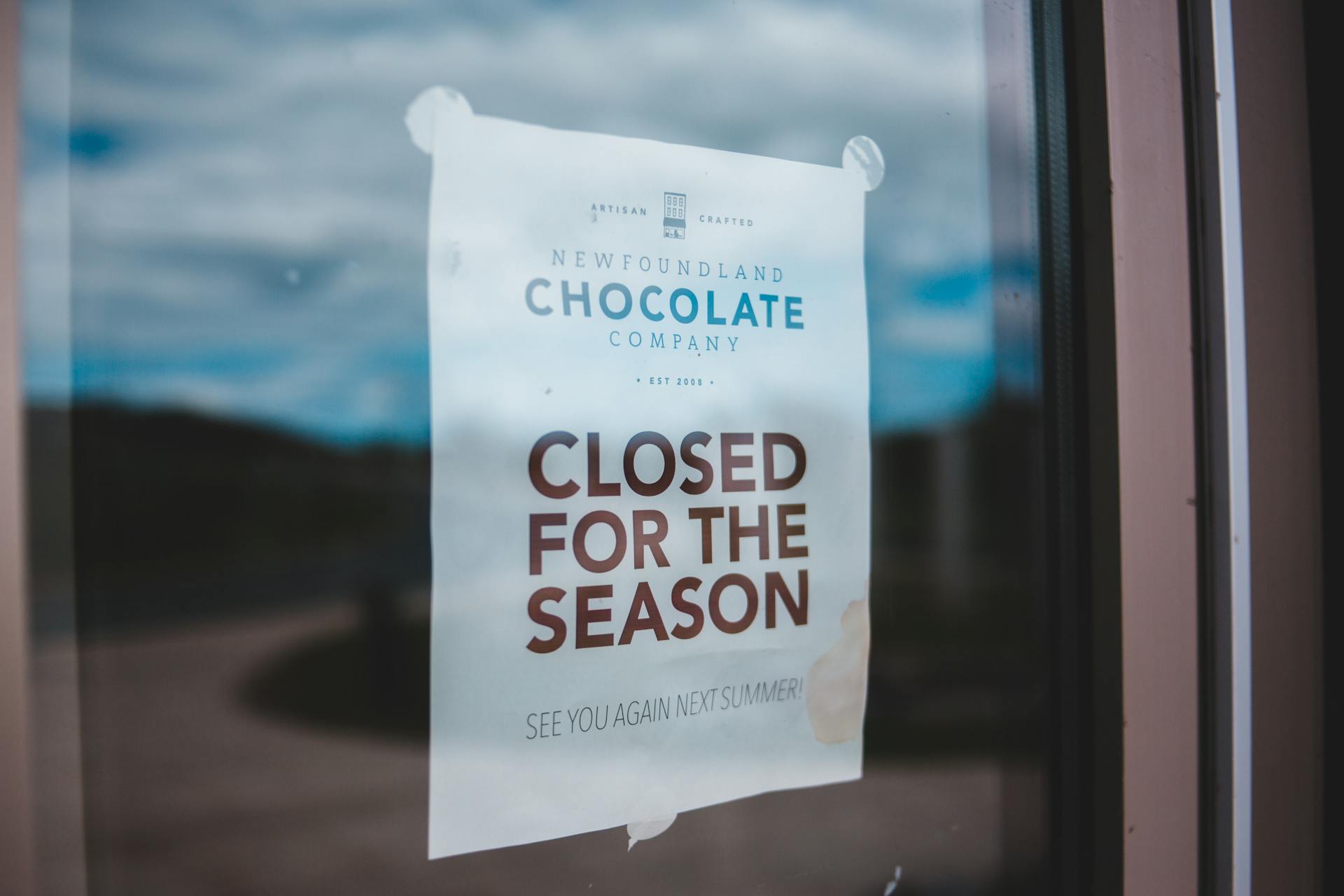 Announcement on white paper with CLOSED FOR THE SEASON inscription attached to glass surface at daytime