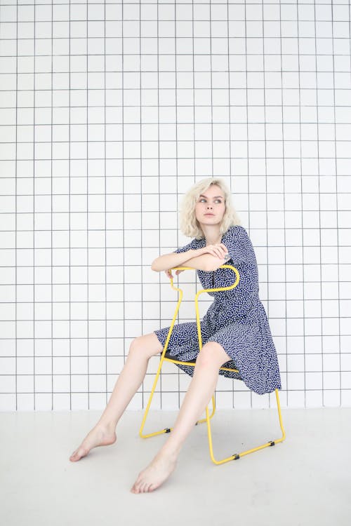 Photo of Girl in Blue Dress While Sitting on Chair