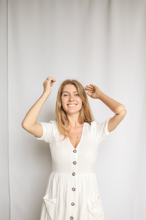 Woman Raising Her Prosthetic Arm Smiling in White Dress